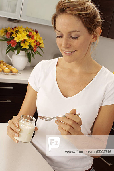 Woman In Kitchen Eating Joghurt