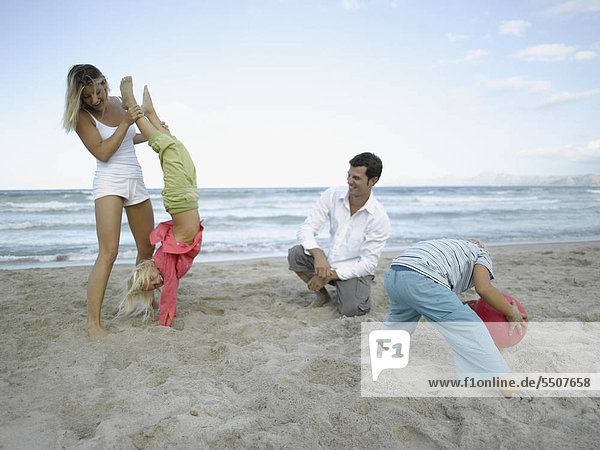 Eltern toben mit Kindern am Strand