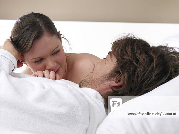 Junges Liebespaar kuschelt im Bett