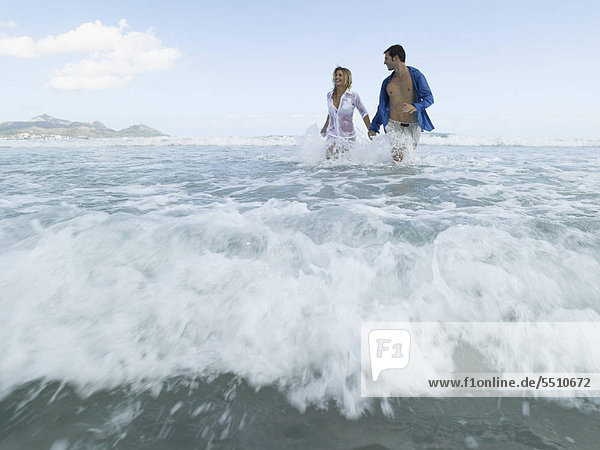 Mid adult couple running on the beach