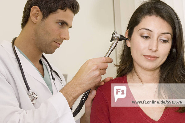 Portrait of young doctor examining female patient