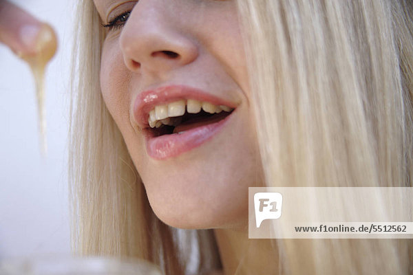 Young blond Woman lecken Honig aus den Finger  Seitenansicht  hautnah mund