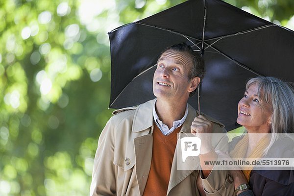 Paar unter einem Regenschirm schaut nach oben
