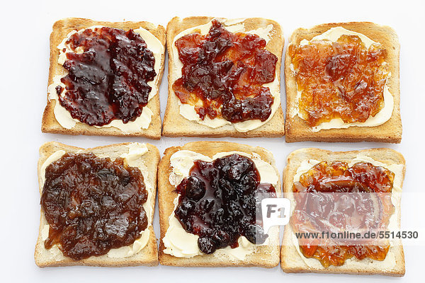 Sechs Scheiben Toastbrot mit verschiedenen Marmeladensorten,  Rhabarbermarmelade,  Aprikosenmarmelade,  Erdbeermarmelade,  Orangenmarmelade,  Kirschmarmelade,  Ingwermarmelade
