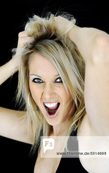 Blonde young woman grabbing her hair and screaming  portrait