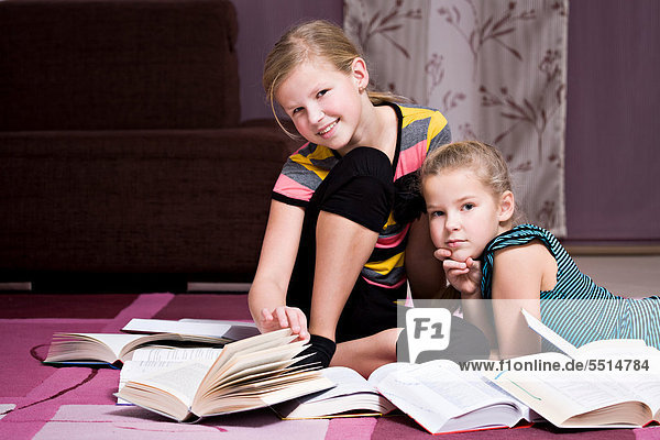 Girsl  11 and 8  sitting and lying between books