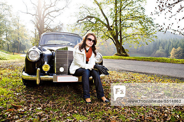 Young woman in front of a post-war classic car