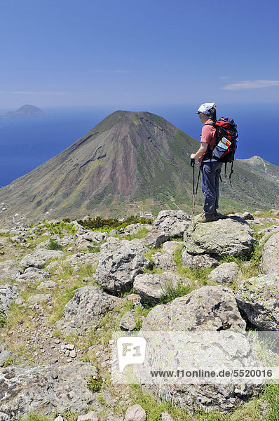 Hiker in front of a volcano on Salina  with the islands of Filicudi and Alicudi at the rear  Aeolian or Lipari Islands  Sicily  Southern Italy  Italy  Europe