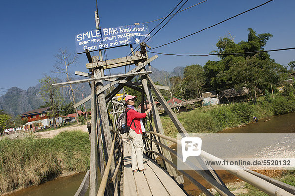 Vientiane Hauptstadt Frau gehen über Fluss Gesang Holzbrücke Vietnam Asien Laos Lied Vang Vieng