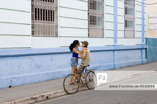 Junges Liebespaar mit einem Fahrrad am Straßenrand  Camaguey  Kuba