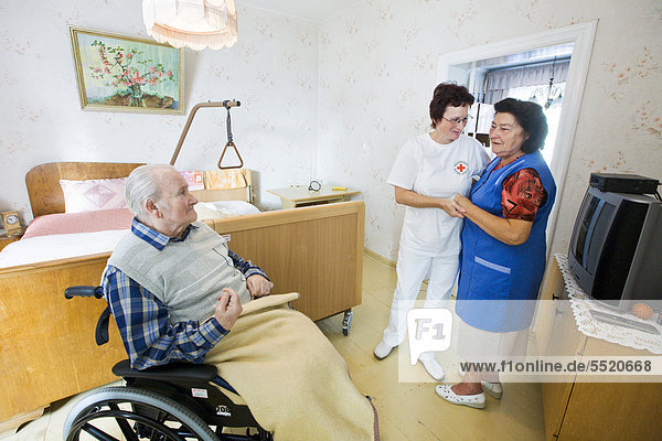 Outpatient care provided by the German Red Cross  nurse Anke Lehmann visits an elderly couple every morning to help the wife of dementia suffering husband  to lift him from bed into the wheelchair  Brandenburg  Germany  Europe