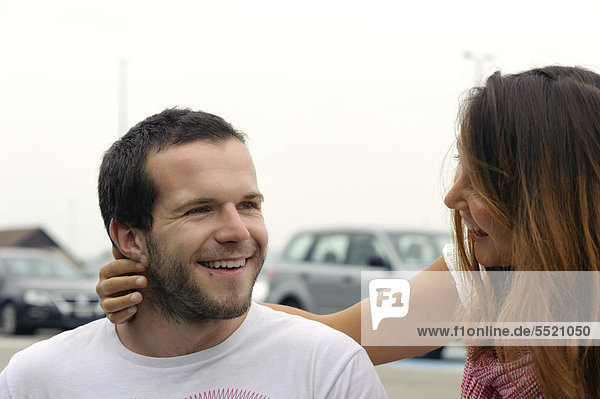 Ein junges Paar begrüßt sich auf dem Parkplatz des EuroAirport  Flughafen Basel Mulhouse Freiburg  Schweiz  Frankreich  Europa  ÖffentlicherGrund