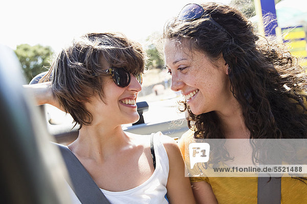 Women smiling together in convertible