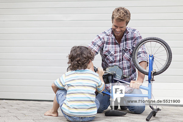Father helping son fix bicycle