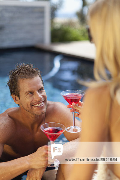 Couple toasting each other in pool