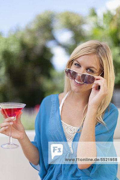 Smiling woman having cocktail outdoors