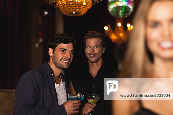 Lächelnde Männer beim Cocktail im Club