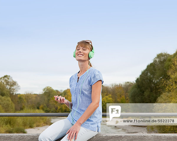 Außenaufnahme  Frau  zuhören  Kopfhörer  freie Natur