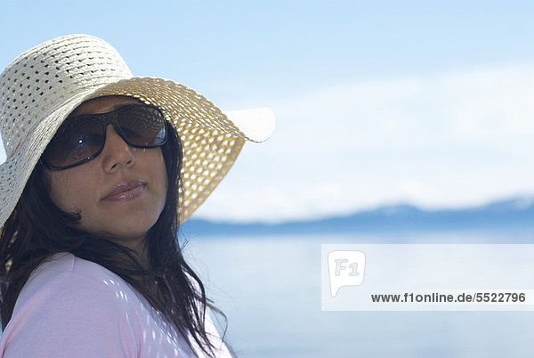 Woman wearing sunhat by lake