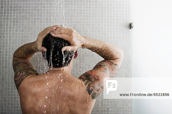 Mann wäscht sich die Haare unter der Dusche