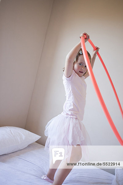 Girl playing with hula hoop in bedroom