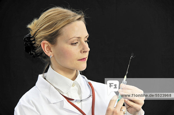 Assistenzärztin  junge Ärztin bereitet eine Spritze vor
