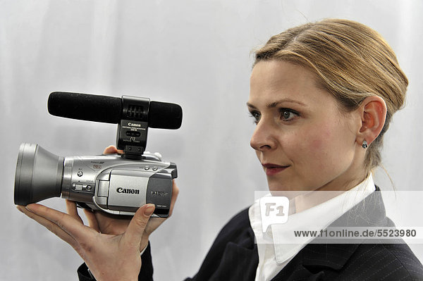 Junge professionelle Videofilmerin beim Filmen mit Filmkamera