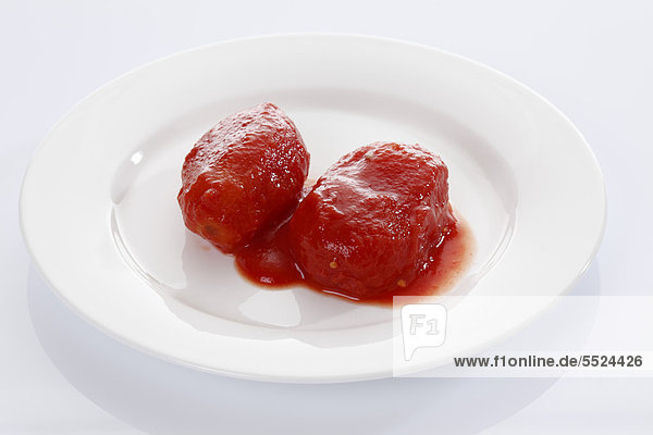 Zwei geschälte Tomaten aus der Dose auf weißem Teller