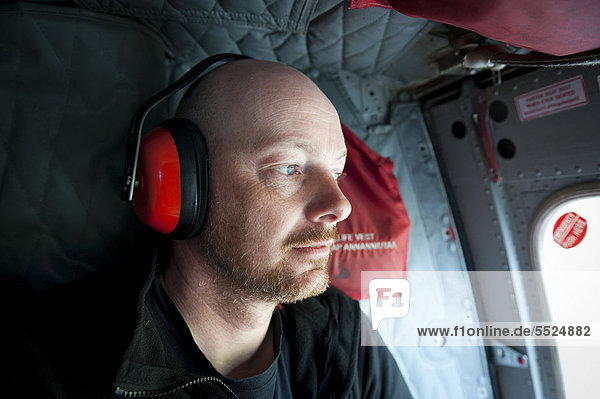 Tourist wearing ear protection  Air Greenland helicopter  Tasiilaq  Ammassalik Peninsula  East Greenland  Greenland