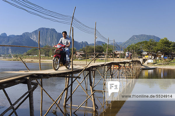 Moped rider crossing the bamboo bridge over the Nam Song River  karst mountains  Vang Vieng  Vientiane  Laos  Indochina  Asia