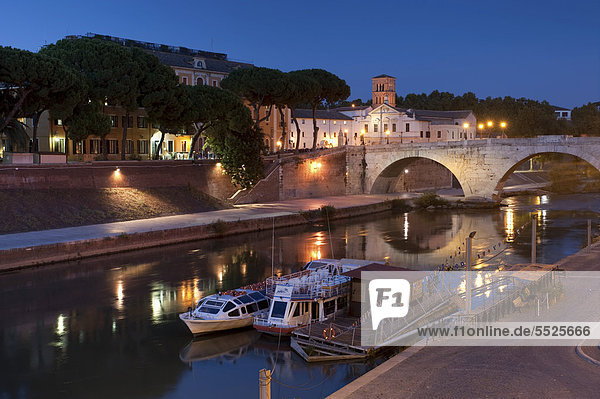 Der Fluss Tiber  die Tiberinsel und die Ponte Cestio in der Abenddämmerung mit Ausflugsbooten  Rom  Italien  Europa
