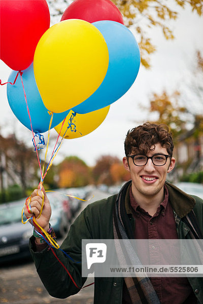 Junger Mann Betrieb bunte Luftballons  portrait
