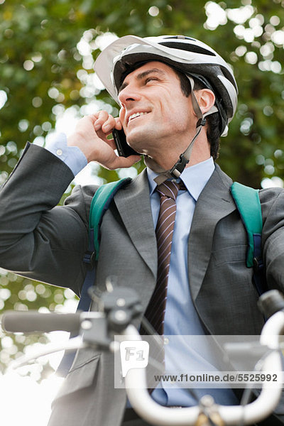 Mid adult businessman using cellphone on bicycle
