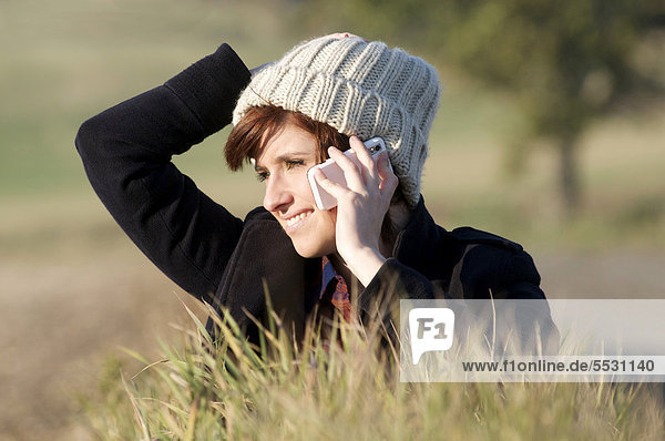 Junge Frau telefoniert mit einem Handy in freier Natur