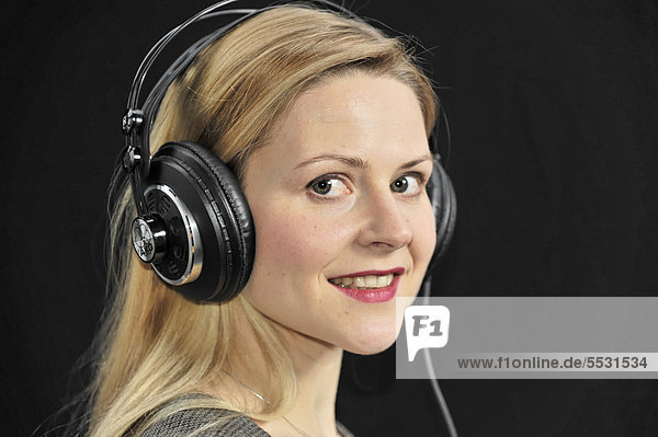Junge Frau hört mit Kopfhörer Musik