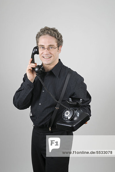 Businessman wearing a black suit talking on a historical W 38 phone