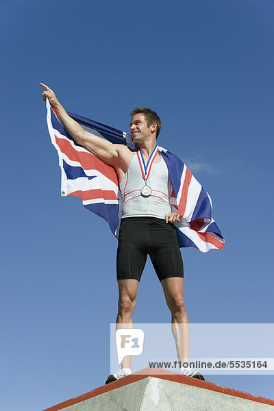 Männlicher Athlet auf dem Siegerpodest mit britischer Flagge