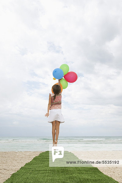 Mädchen springen mit Luftballons  nach Himmel greifen  Rückansicht