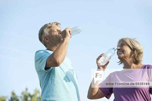 Seniorenpaar trinkt Flaschenwasser im Freien