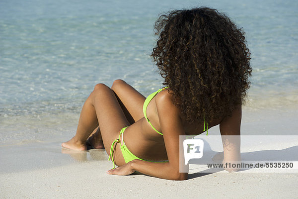 Frau entspannt am Strand  Blick aufs Meer  Rückansicht