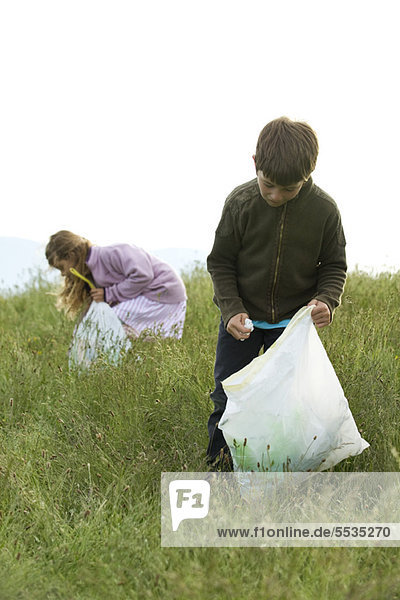 Children picking up trash in field