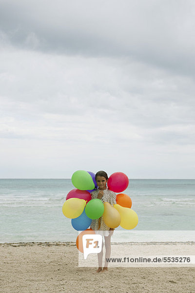 Mädchen mit bunten Luftballons am Strand