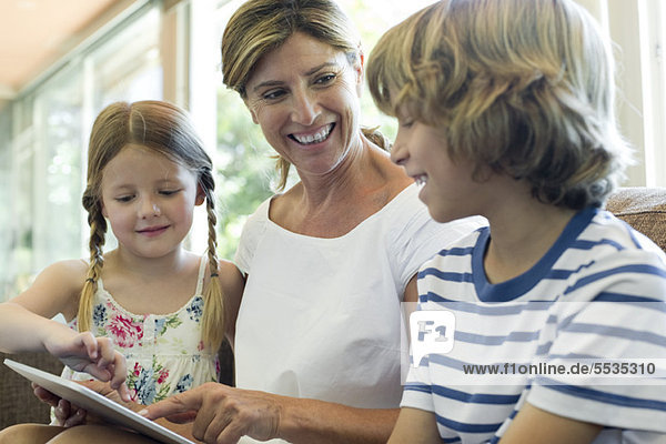 Grandmother and grandchildren using digital tablet