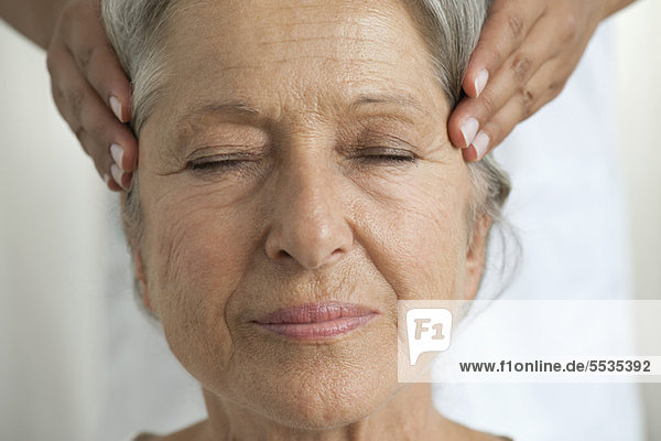 Senior woman having her temples massaged  cropped