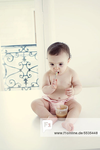 Infant eating baby food with spoon  portrait