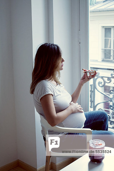 Schwangere Frau isst Toast mit Marmelade