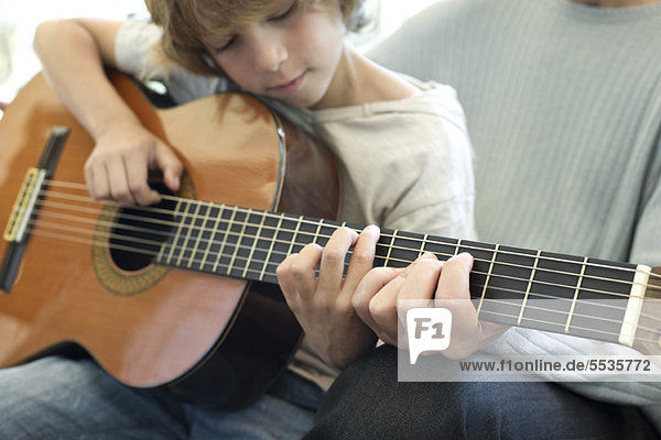 Junge lernt mit Vater Gitarre spielen