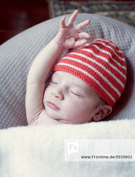 Neugeborenes Baby schläft mit angehobenem Arm