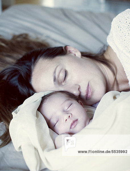 Mutter und Neugeborenes schlafen im Bett
