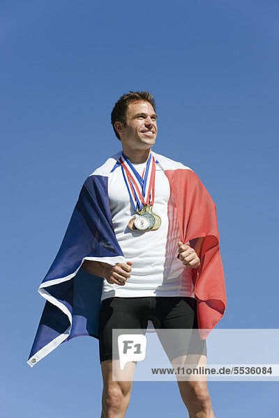 Männlicher Athlet wird auf dem Podium geehrt  in französische Flagge gehüllt
